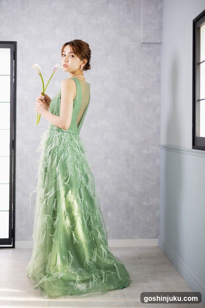 Woman in Green Feather Dress Holding Flowers