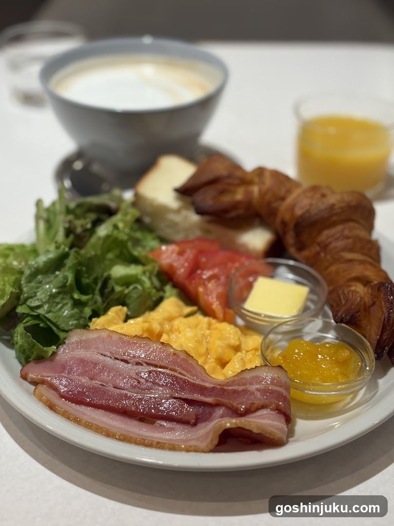 Breakfast Plate with Croissant, Bacon, Scrambled Eggs, Salad, Tomato, Butter and Jam