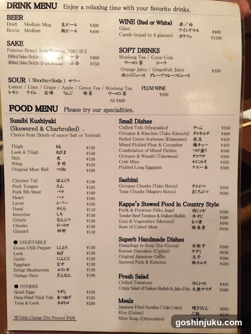 A printed menu listing beverages (beer, sake, sour drinks, wine) and food items (skewers, small dishes, sashimi, country style meals), with prices in yen.