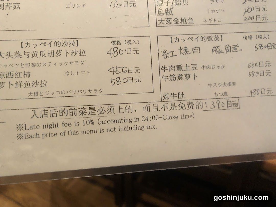 A printed menu page showing salad and hot dishes with prices in yen, including handwritten notes.