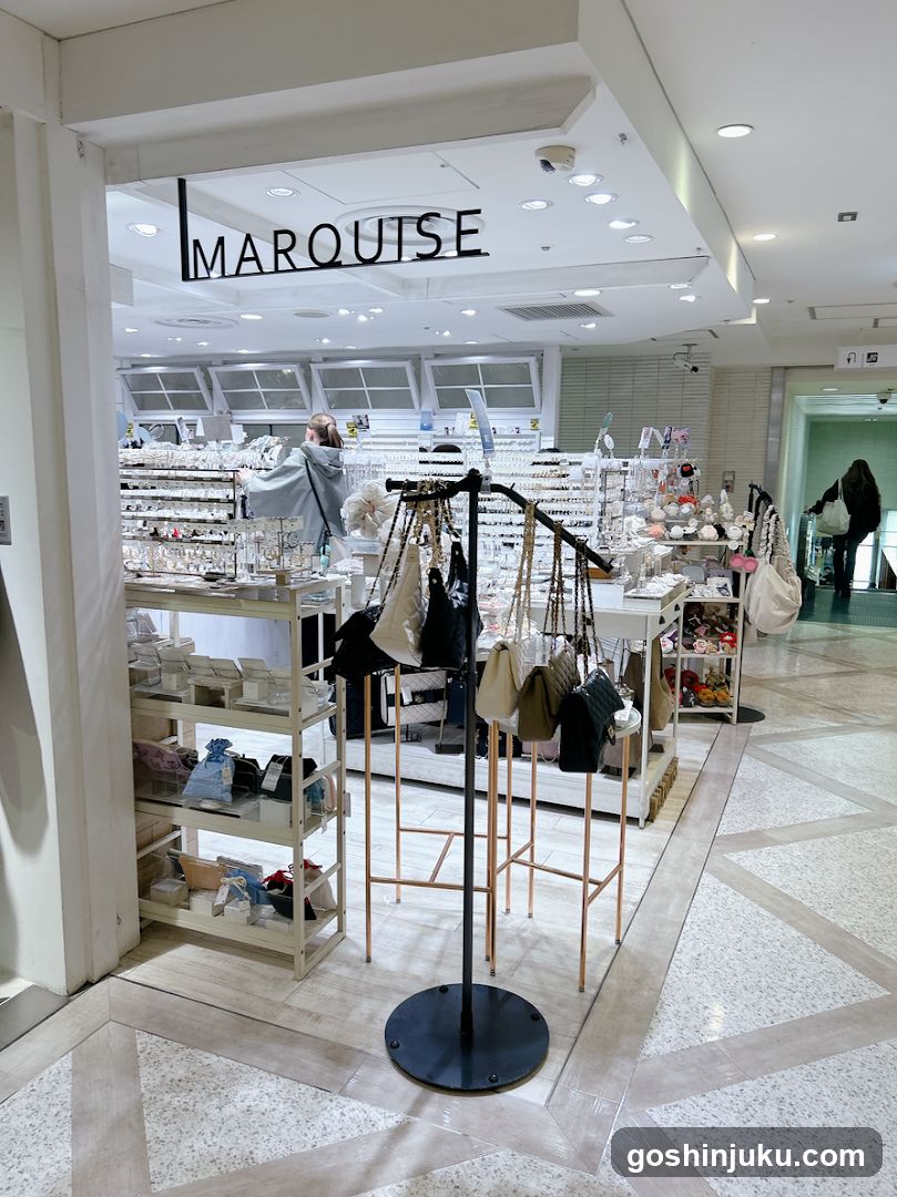 Interior view of a jewelry store named MARQUISE, visible through the entrance. The store features multiple display racks with earrings and necklaces hanging on stands. A woman is browsing near the back. Shelves hold boxes and accessories. The floor has a patterned tile design.
