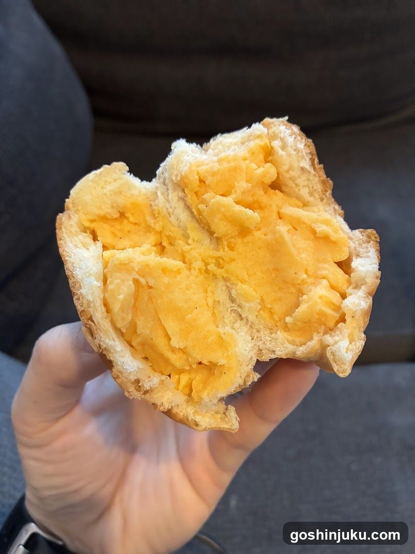 Hand holding a bitten pastry with yellow filling