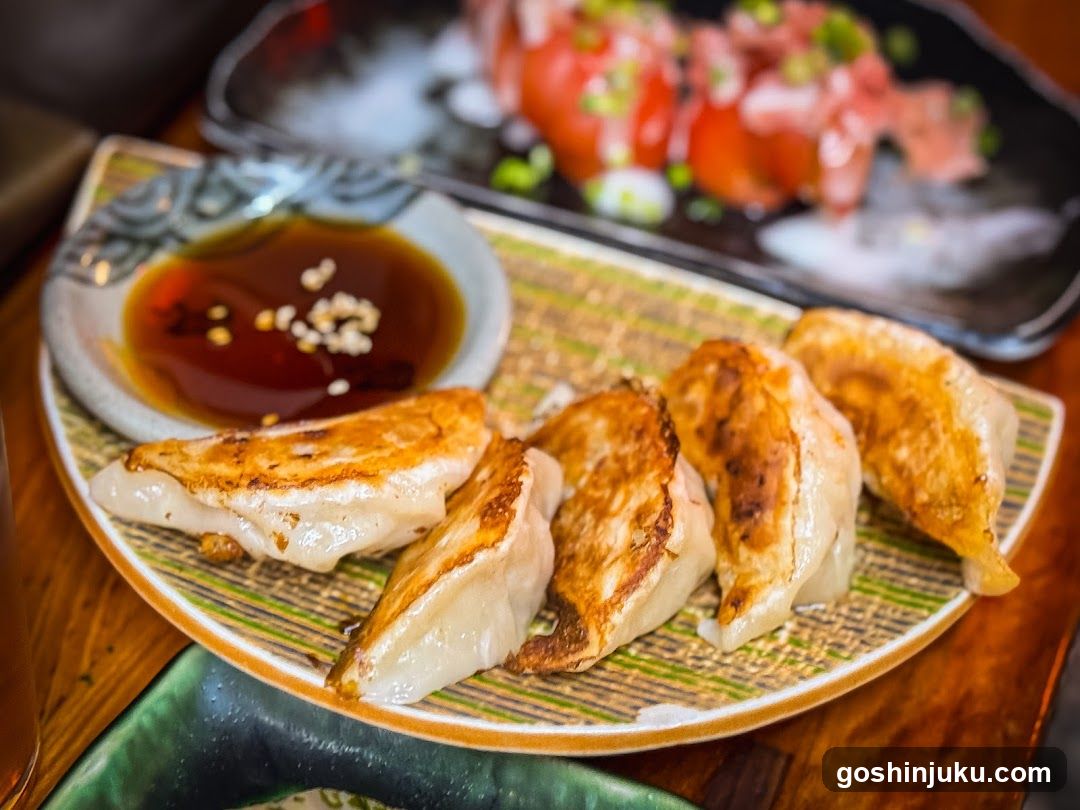 Gyoza with dipping sauce and sashimi in background