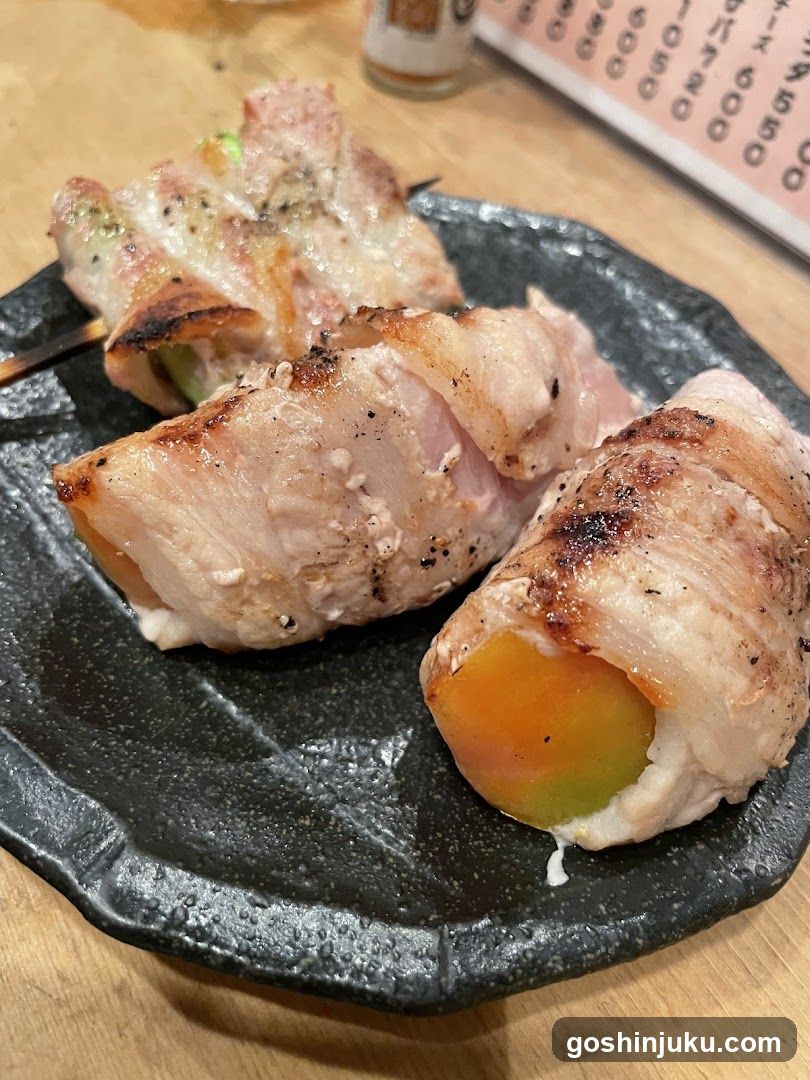 Bacon-wrapped food skewers on a dark plate