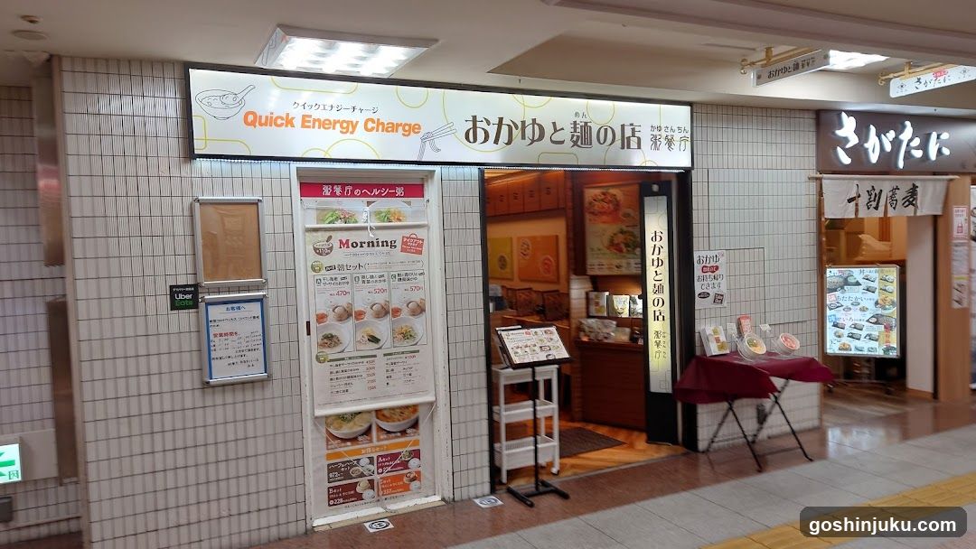 A storefront with a tiled facade and signage reading 'Quick Energy Charge' and 'Oka-yu to Men no Te'. A menu board is visible on the door, displaying various food items.