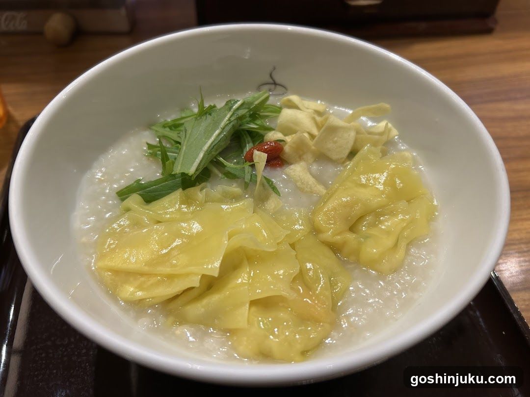 Bowl of congee with wontons and greens