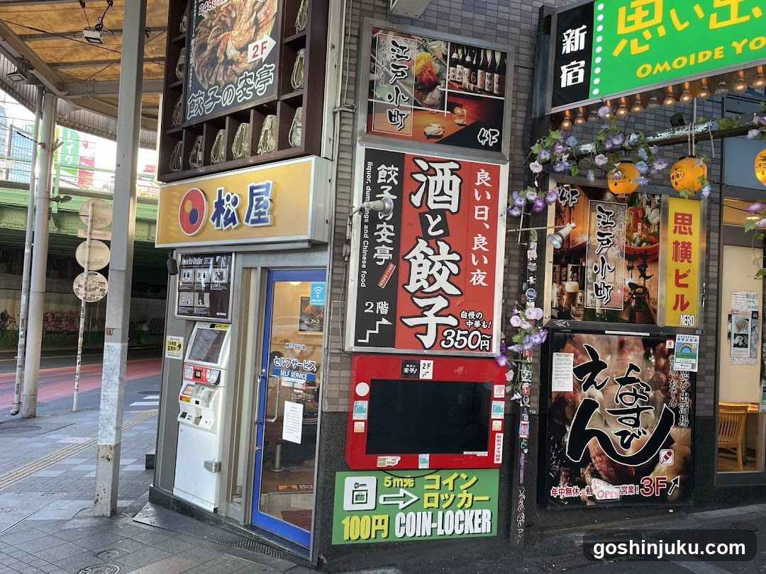 The image shows the exterior of several dining establishments, including a sushi restaurant and a bar with a coin locker.