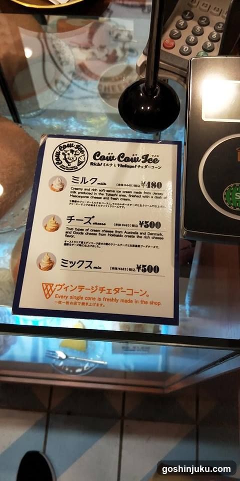 A close-up of a menu board displaying ice cream cone options with prices in yen and English descriptions.