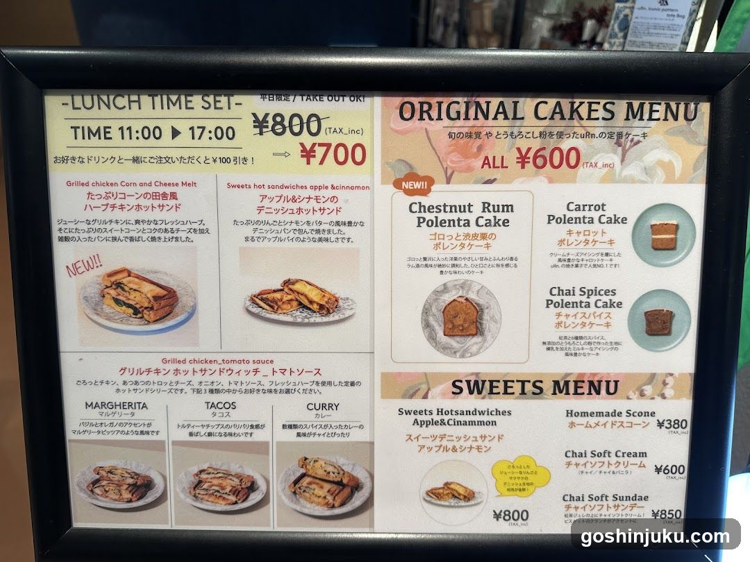A framed menu board displaying lunch sets, original cakes, and sweets with prices in yen.
