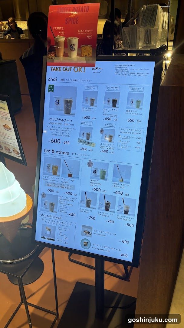 A digital menu board displaying takeout options including chai, tea & others, and soft cream desserts with prices in yen.