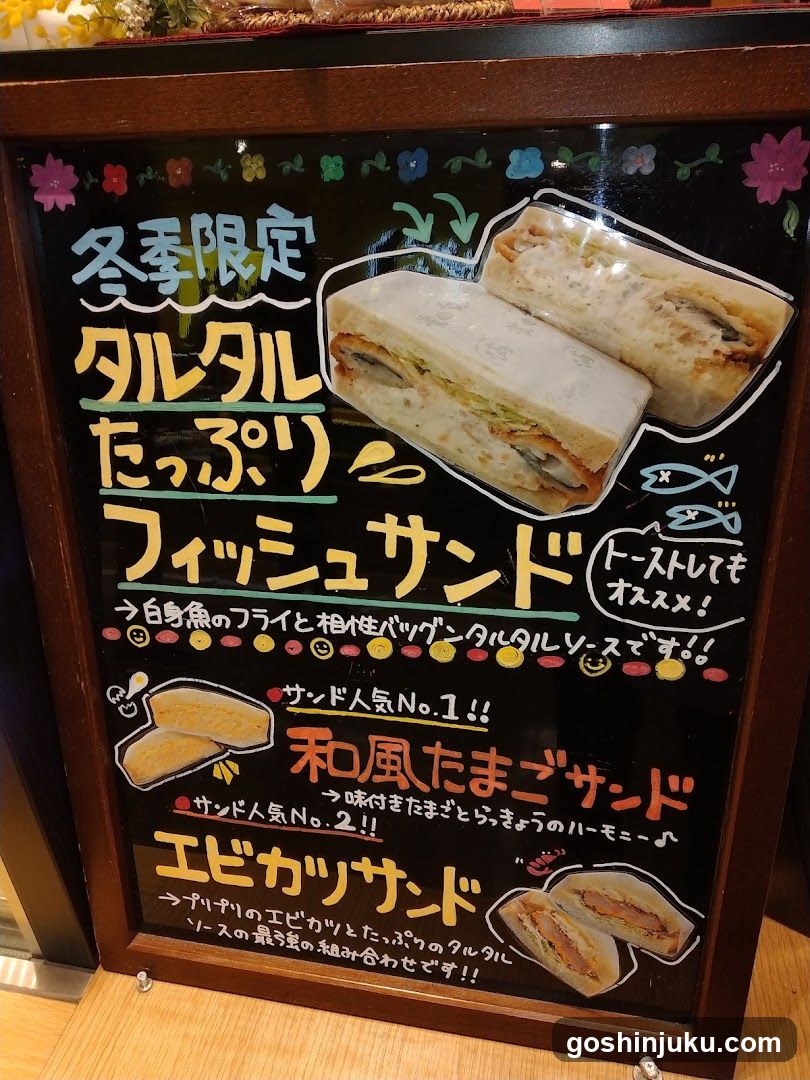 A framed menu board displaying three winter-limited sandwich items with Japanese text and images of the sandwiches.