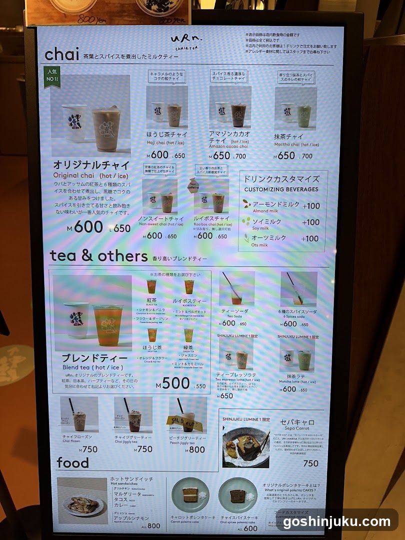 Digital display menu at a cafe featuring chai, teas, blends, and food items with prices in yen.