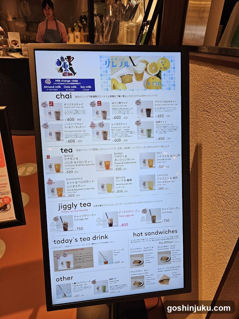 A digital menu display showing chai tea, hot sandwiches, and other items with prices in yen.