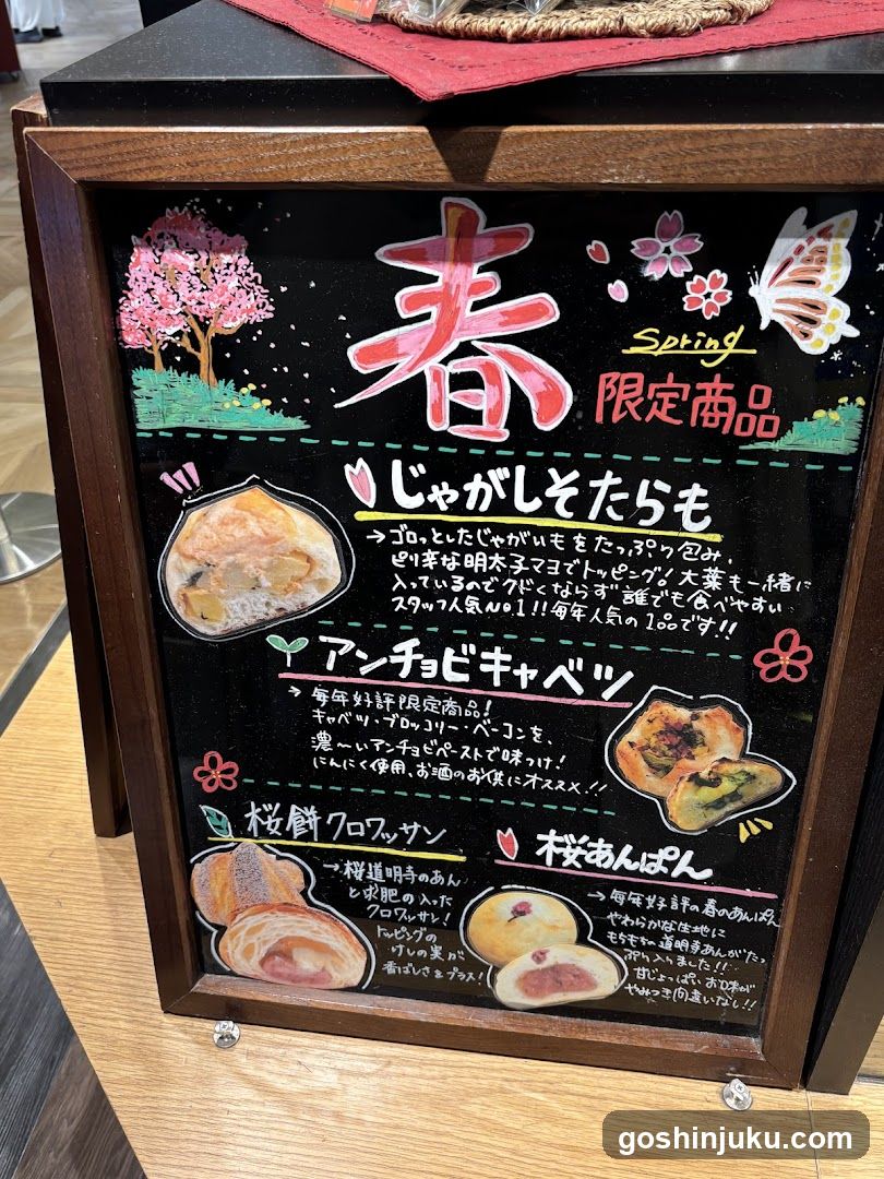 A framed menu board displaying spring-themed limited items with Japanese text and illustrations of food products.