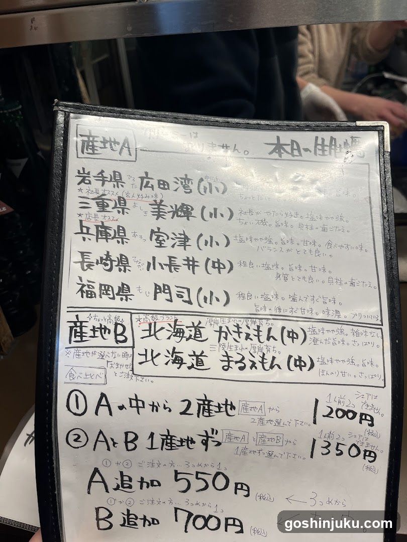 Handwritten menu board listing sake varieties from Japan's regions, including 'Iwate Prefecture Hirota Bay (Small)' and 'Mie Prefecture Ueda (Medium)', with prices like ¥1200 and ¥1350.