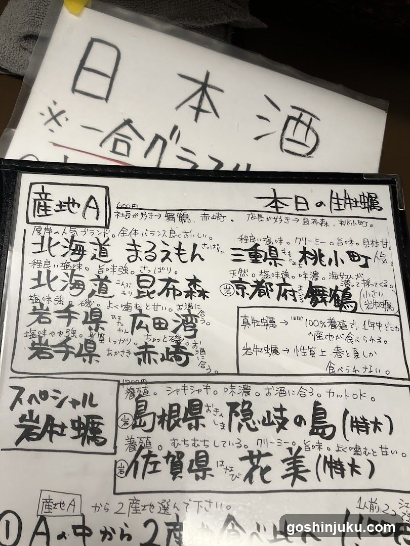 A close-up photo of a handwritten menu board on a whiteboard, featuring various Japanese sake options with descriptions and prices. The top section lists 'Japan Sake' with a price of ¥1000. Below are sections labeled 'Producer A', 'Today's Selection', and 'Special', detailing different types of sake from regions like Hokkaido, Aomori, and Ibaraki.