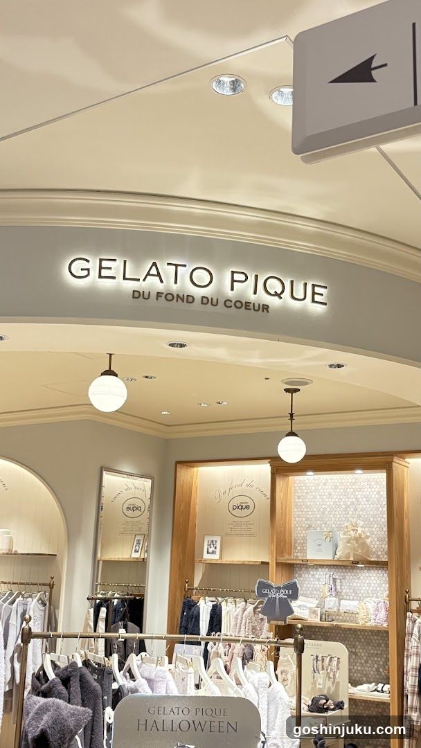 Interior view of a retail store with signage reading 'GELATO PIQUE DU FOND DU COEUR'. Clothing racks display garments, including a Halloween-themed section. Shelves showcase accessories and products under warm lighting.