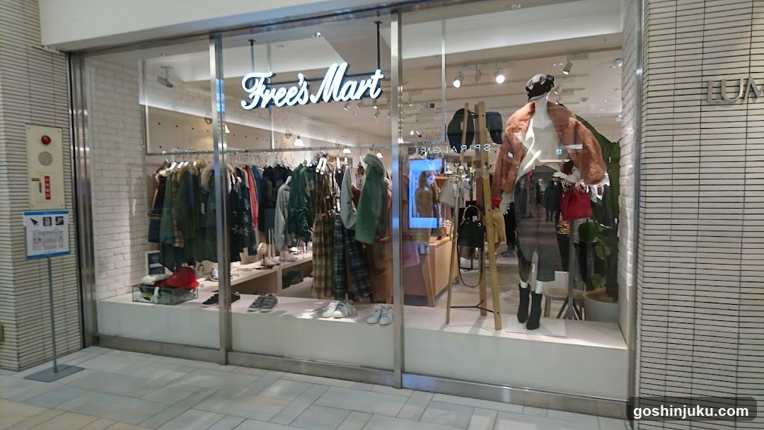 A modern retail store with large glass windows displaying clothing racks and mannequins. The sign 'Free's Mart' is illuminated above the entrance.