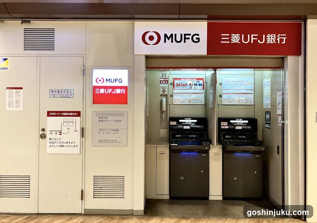 A storefront entrance featuring two ATMs under a MUFG (Mitsubishi UFJ Financial Group) sign with Japanese characters '三菱UFJ銀行'. The left side includes a door with safety notices and an illuminated MUFG logo. The right side shows the ATM area with digital displays and cash dispensers.