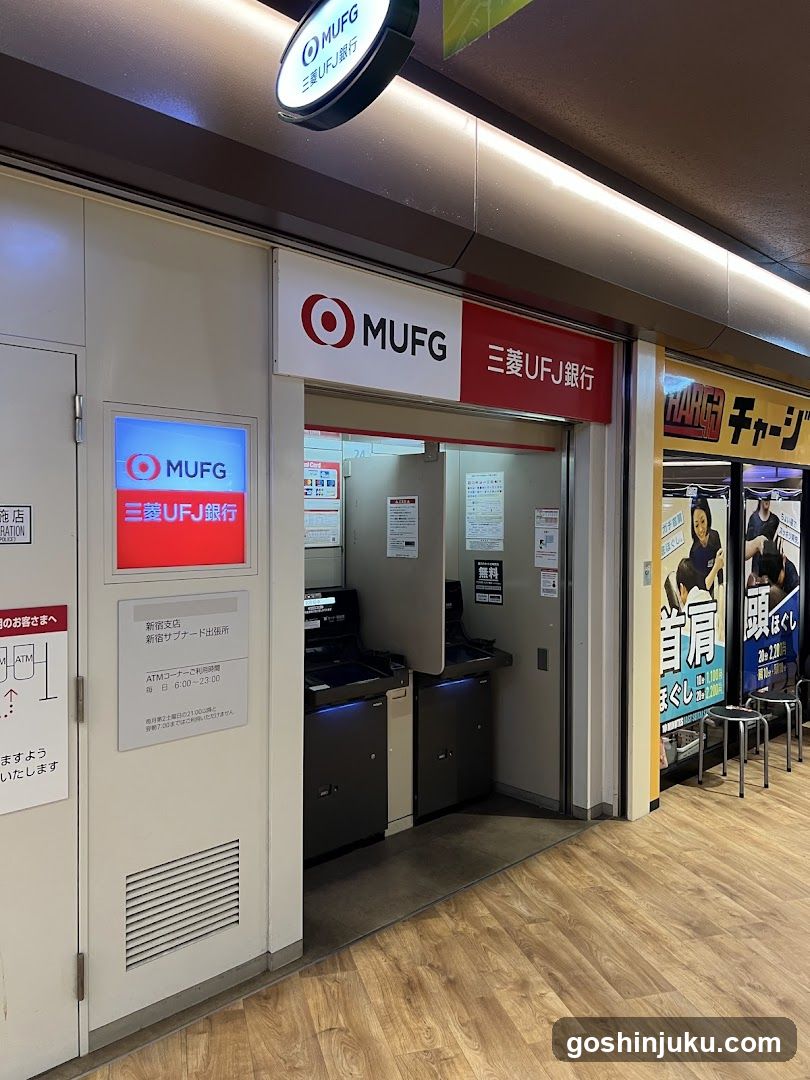 The image shows the entrance of a MUFG (Mitsubishi UFJ Financial Group) bank branch, featuring signage with the bank's logo and name in both English and Japanese. The ATM area is visible through an open doorway, flanked by informational posters and advertisements on adjacent walls.