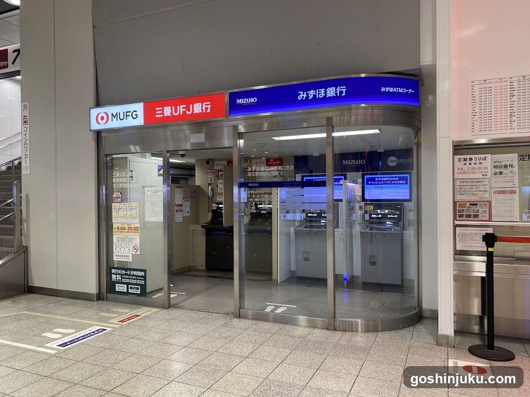 A modern bank entrance featuring glass doors and signage displaying MUFG (Mizuho UFJ Financial Group) branding in both English and Japanese. The interior shows ATMs and banking counters visible through the transparent facade.