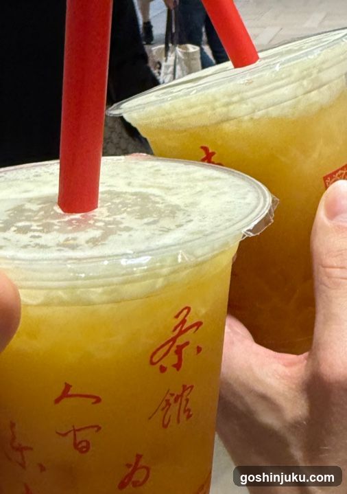Two cups of yellow beverage with red straws