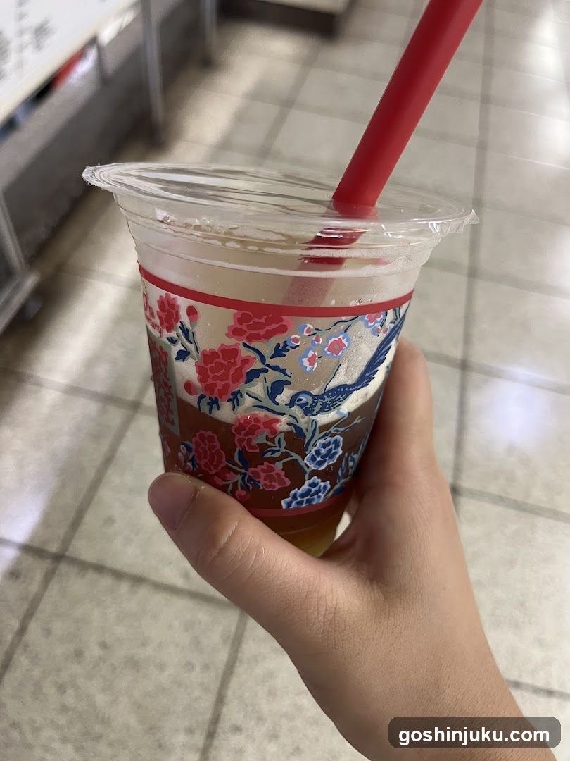 Hand holding a floral-patterned drink cup with red straw