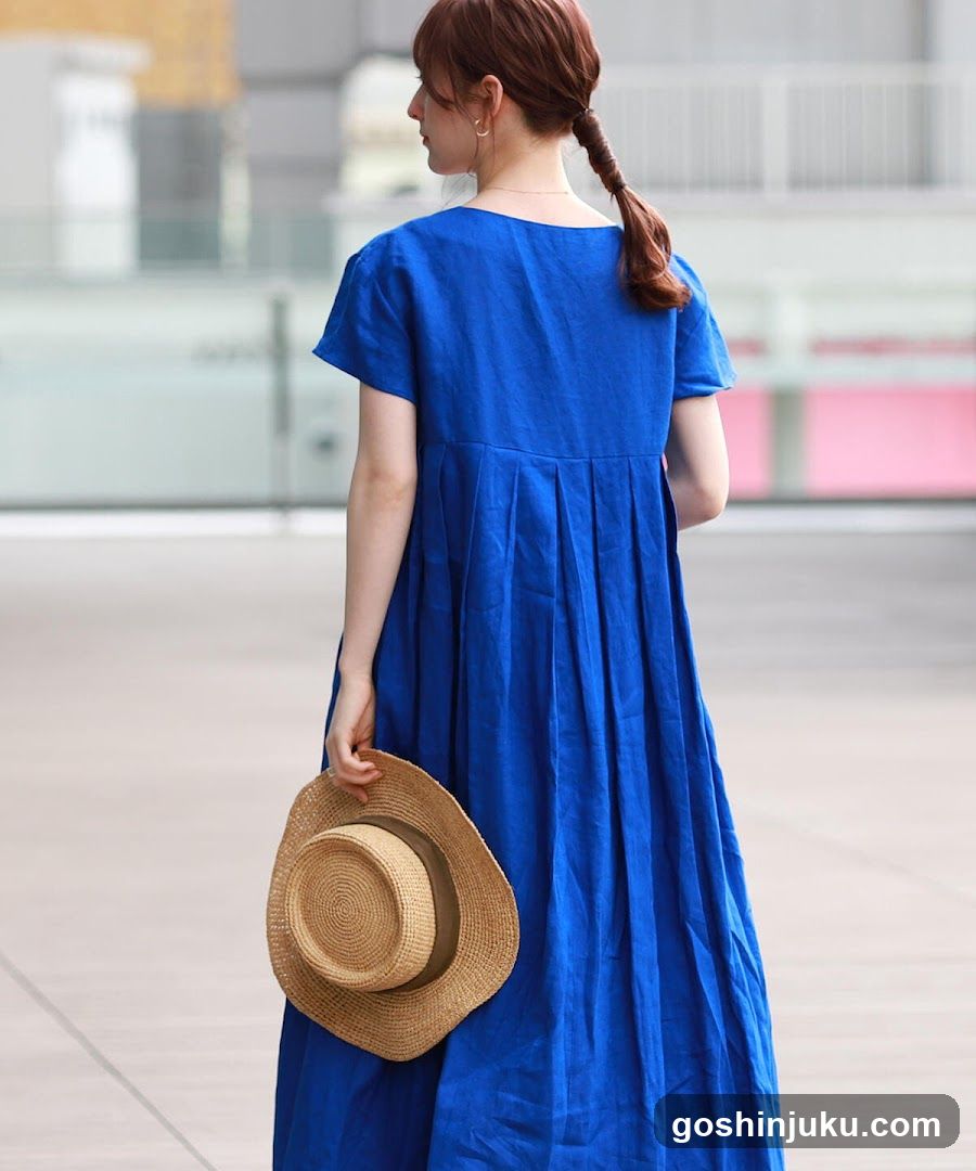 Woman in Blue Dress Holding Straw Hat