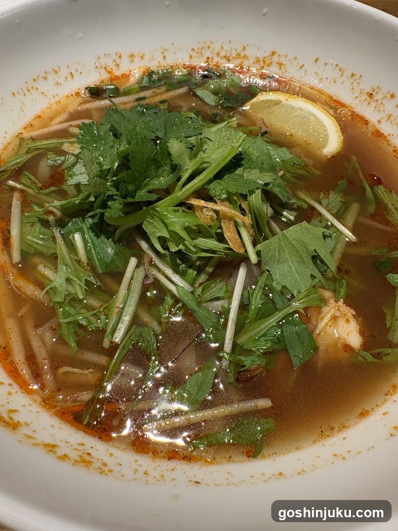 Bowl of Spicy Noodle Soup with Cilantro and Lemon