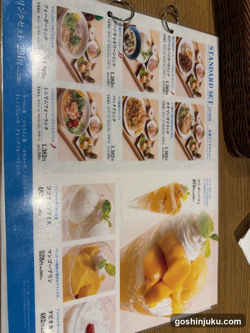A close-up of a printed menu page featuring standard set meals, desserts, and drinks with prices in yen.
