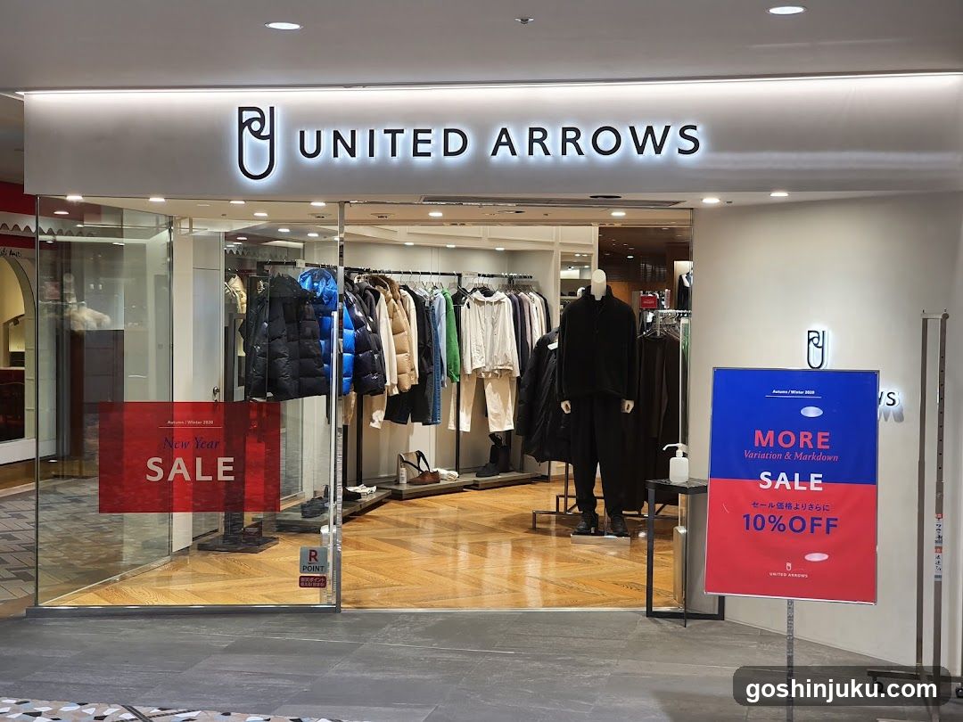 A photo of the physical exterior entrance/storefront facade of a United Arrows store, with visible signage on the building and promotional posters in front.