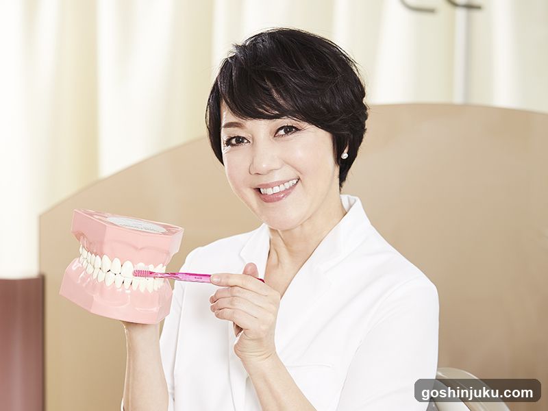Woman demonstrating dental hygiene with toothbrush and model