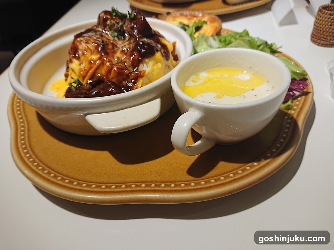 Bowl of savory rice dish with side soup and salad