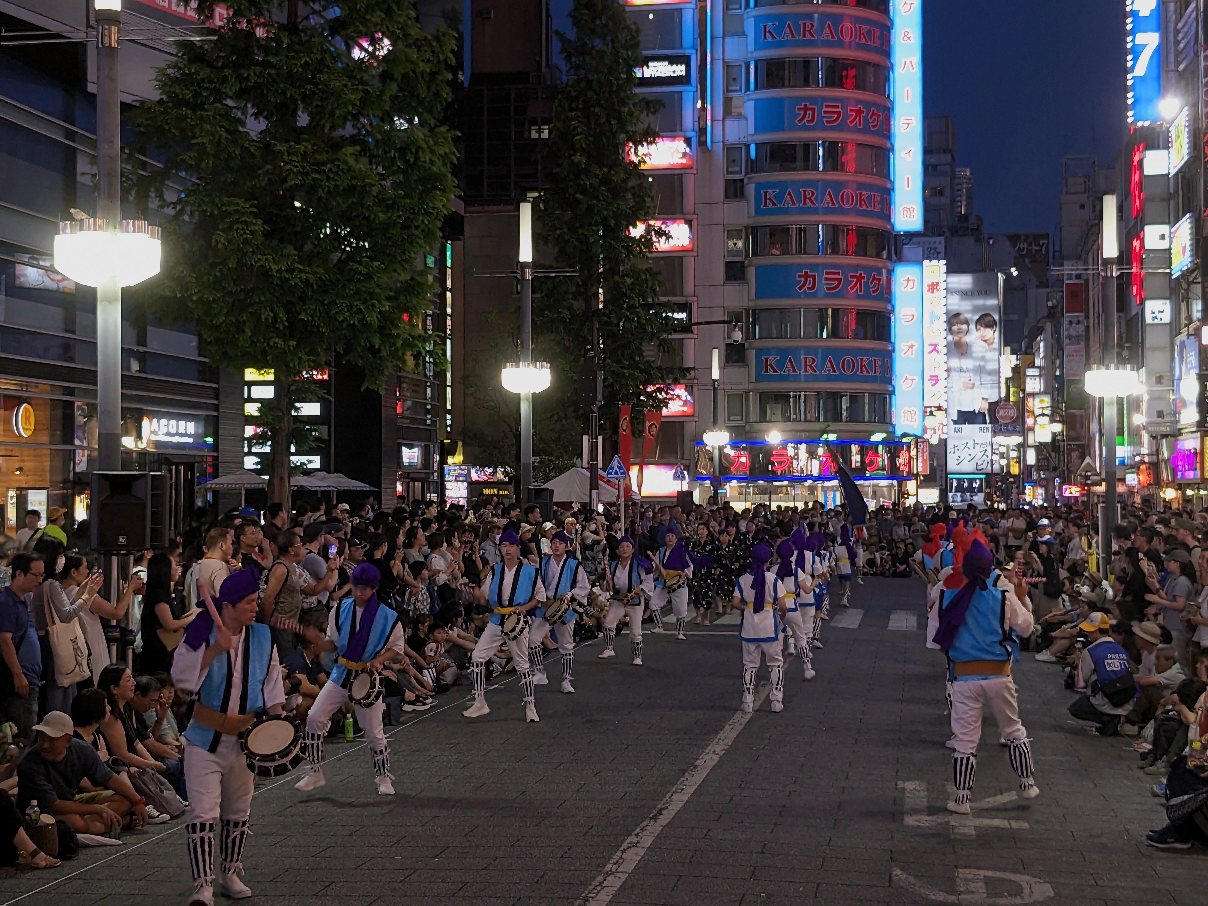 Eisa dancers with taiko drums performing at night under the neon lights of Shinjuku